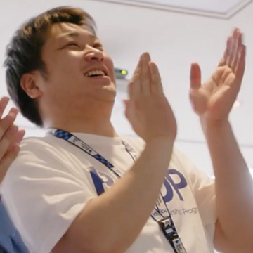 A Bushu employee claps their hands and smiles.