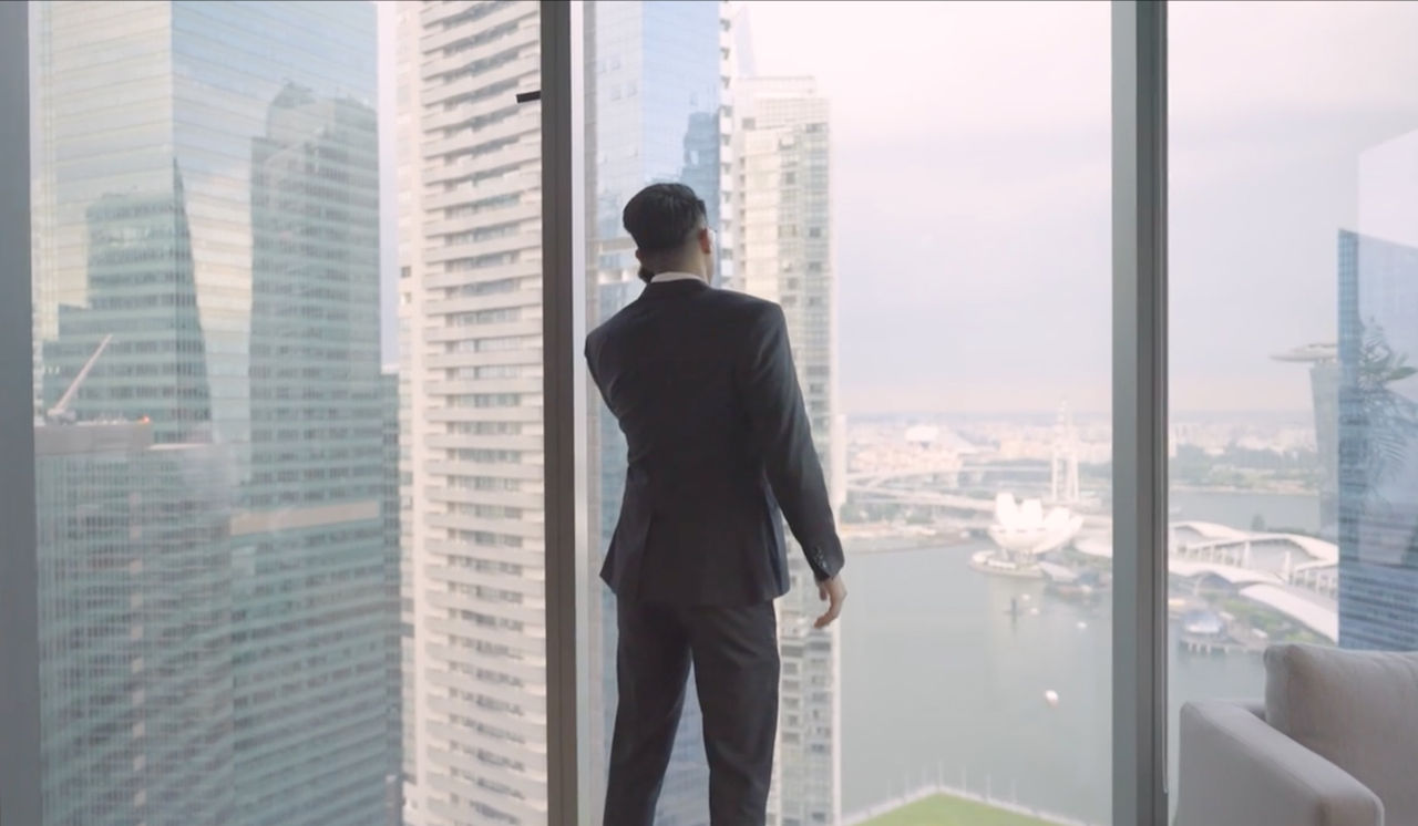 An employee looks out of an office building window while on his mobile phone.